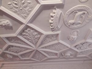 Decorative Stucco ceiling with quilt like patten of diamonds to make flowers. Featuring coat of arms and leaves.