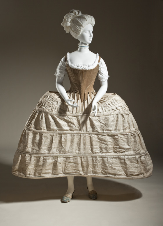 Mannequin wearing a 1700 stays (early version of Corset) and Paniers which were a hoop like structure that went under the gowns so it extended the width of the torso out to either side yet was an oval when seen from above.